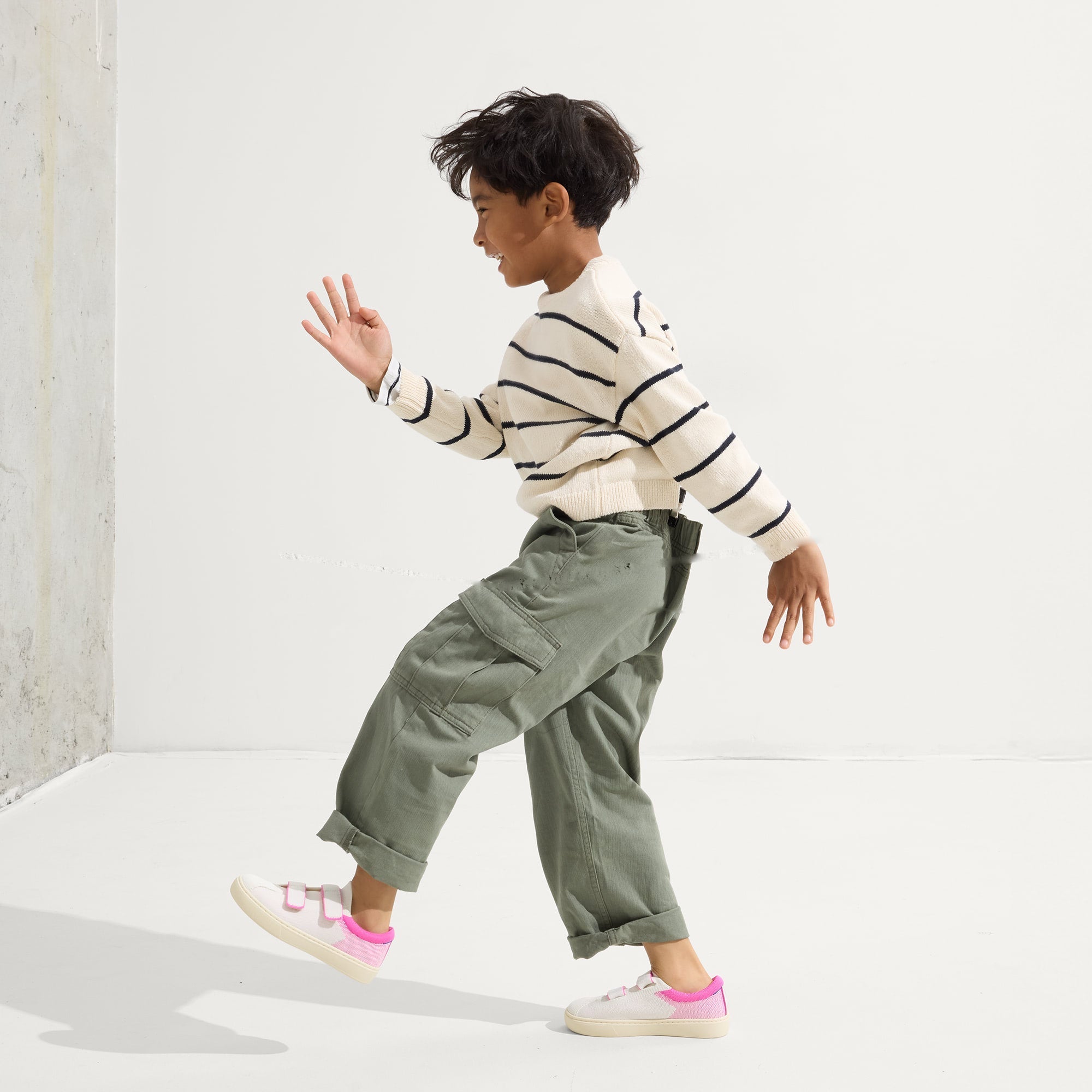model | An alternate image of a child modeling The Kids Strap Sneaker in Pink Taffy. 