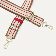 A close-up of The Crossbody Strap in Lollipop Stripe, focusing on the end snap hooks and sliding buckle.