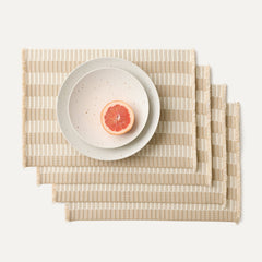 A set of four Placemats in Almond Fringe shown with a plate setting.