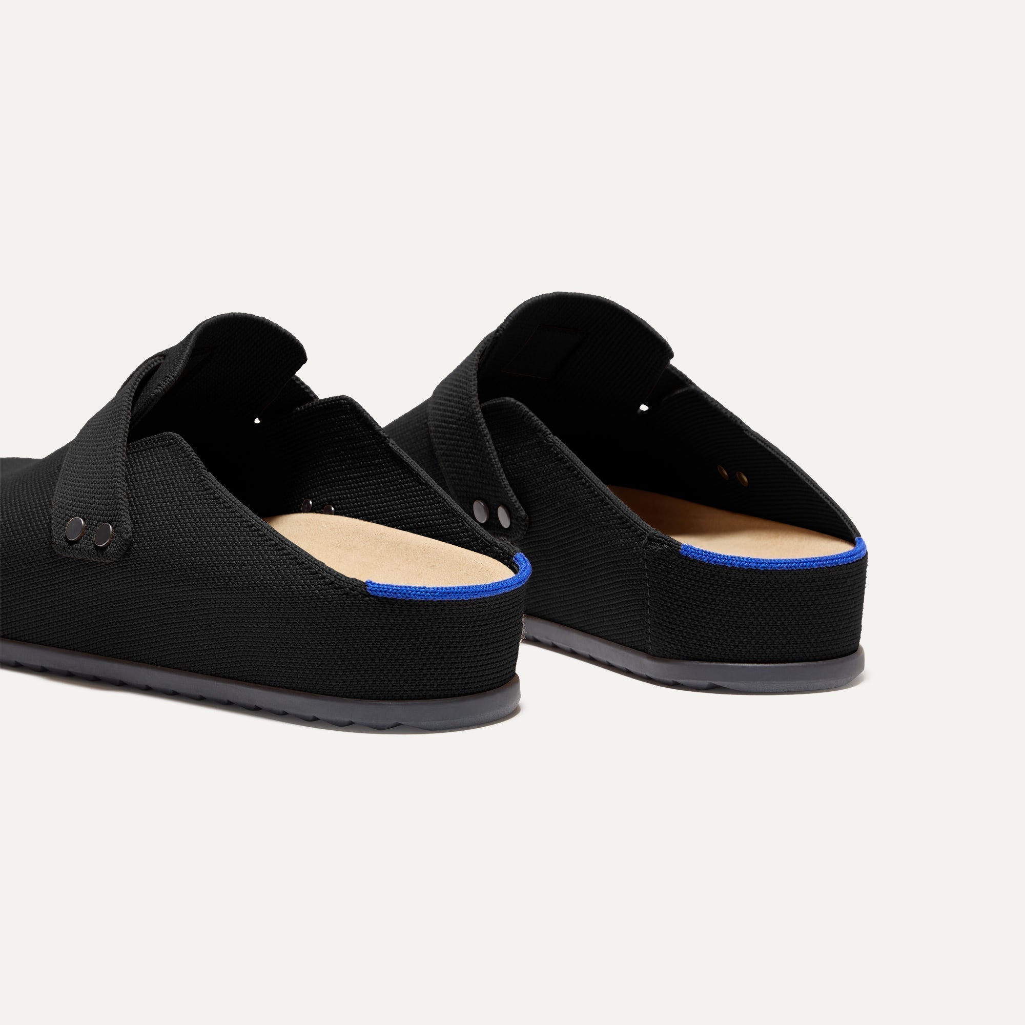 Close up of the heel of The Men's Clog in Soft Black, with Rothy's signature blue halo. 