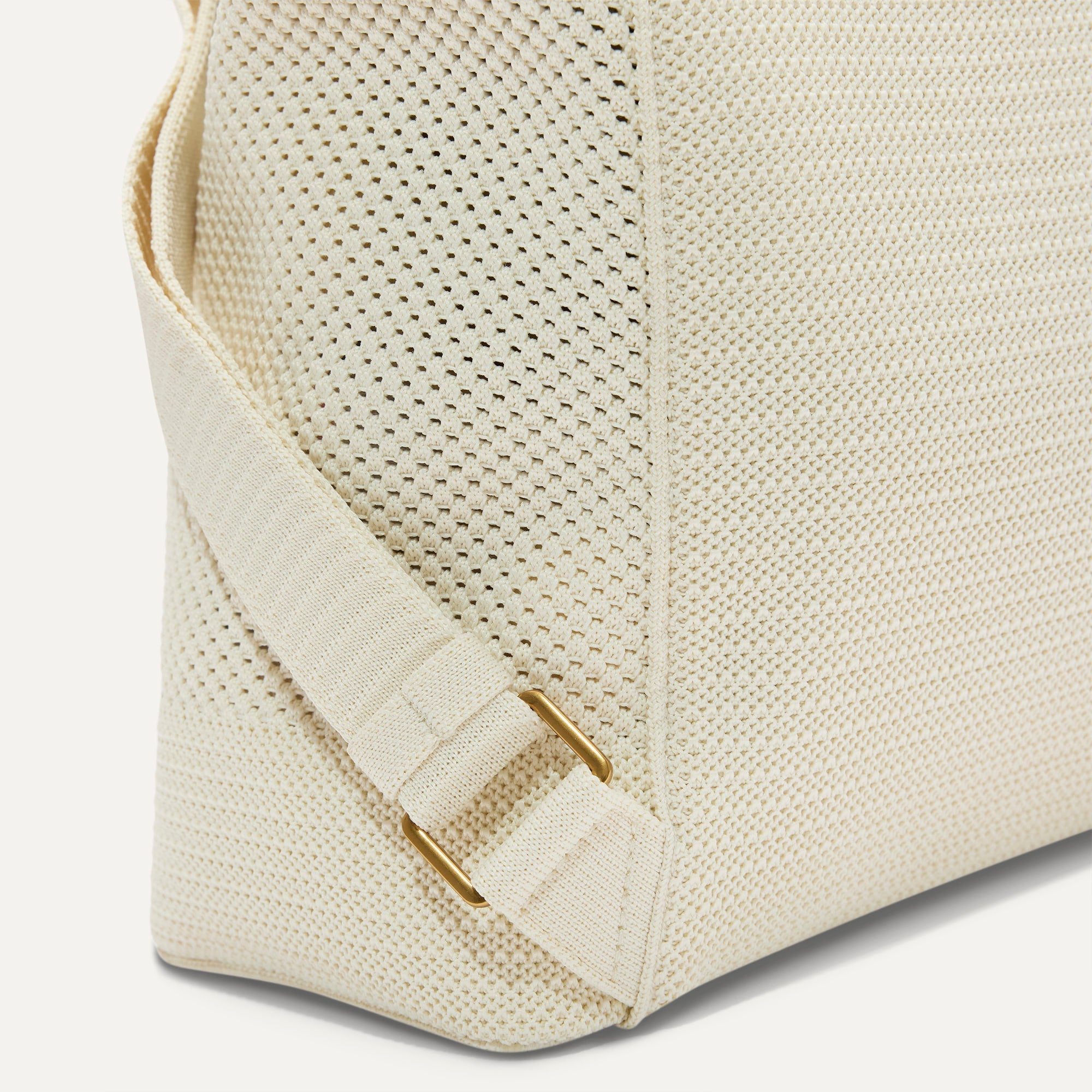 A close up of the The Cinch Backpack in Coconut Crochet focusing on the gold hardware on the straps.