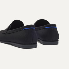 Close up of the heel of The Ravello Penny Loafer in Black, with Rothy's signature blue halo on the pull tab.
