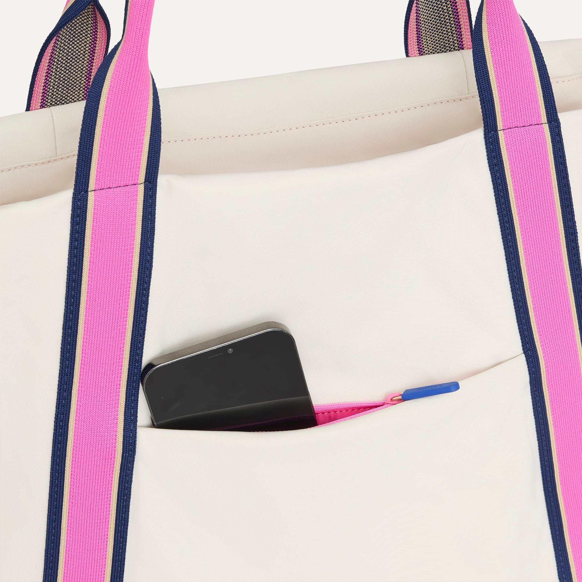 A close up of The Travel Tote in Optic with a phone slipped into the outer pocket.