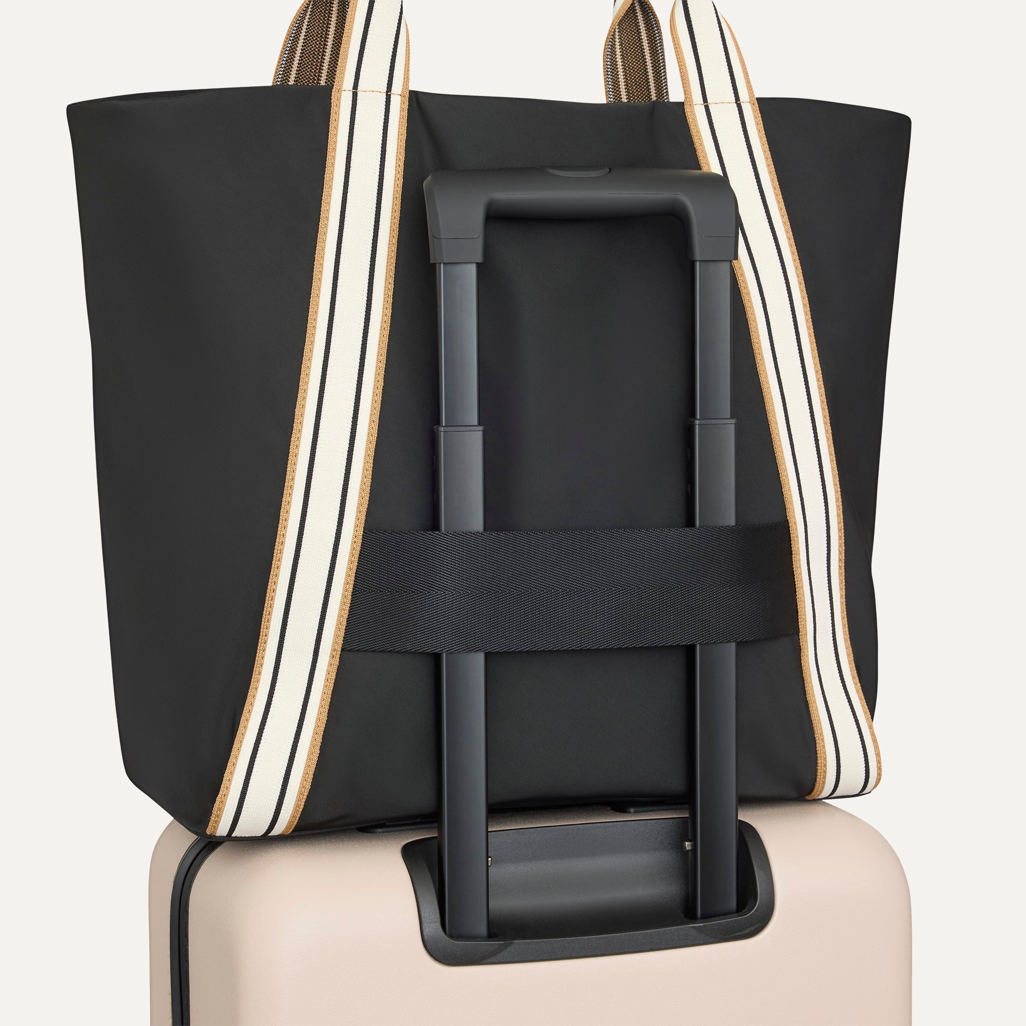 The Travel Tote in Ink, shown attached to a rolling suitcase using the wrap-around band.