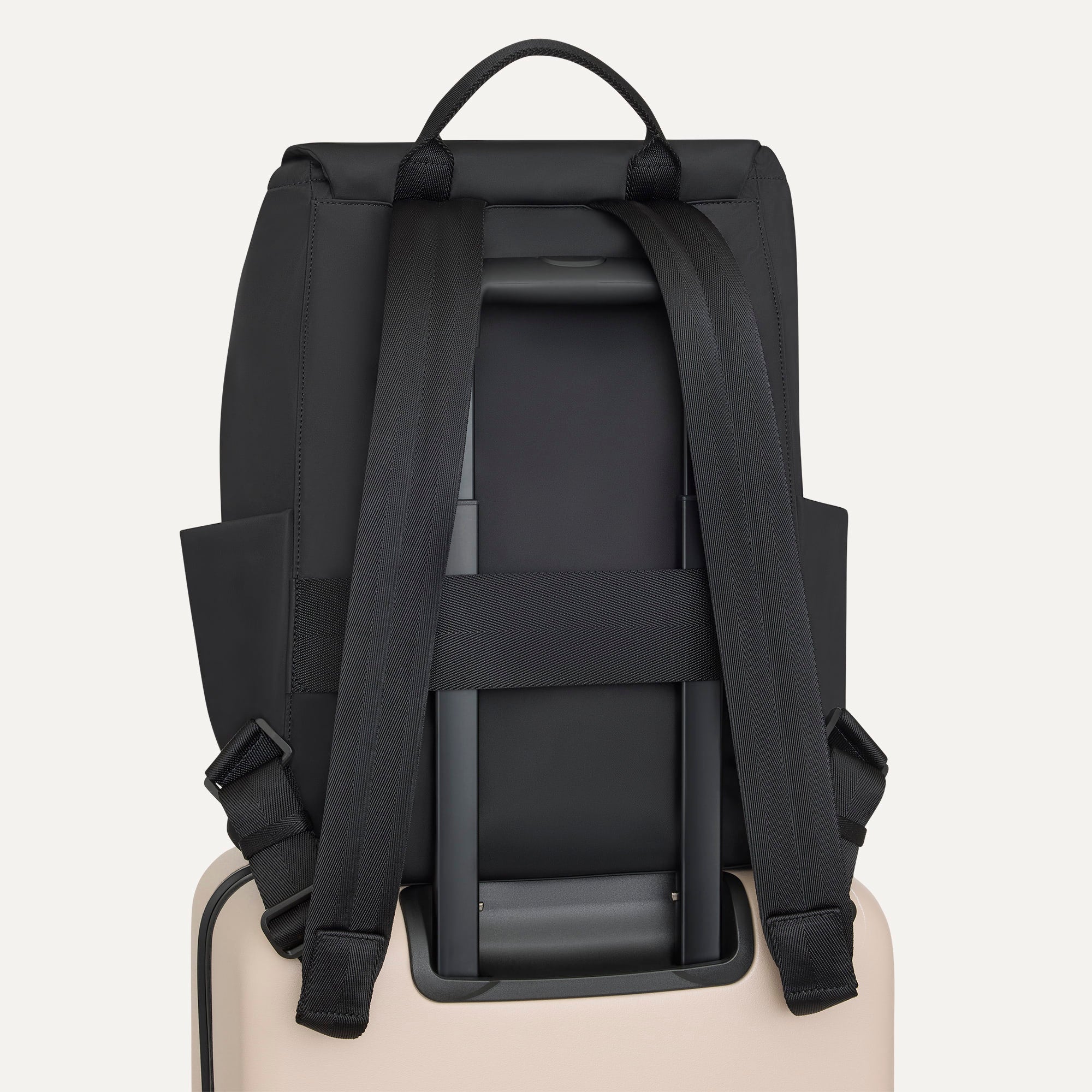 The Travel Cinch Backpack in Ink shown from the back, shown attached to a rolling suitcase using the wrap-around band.