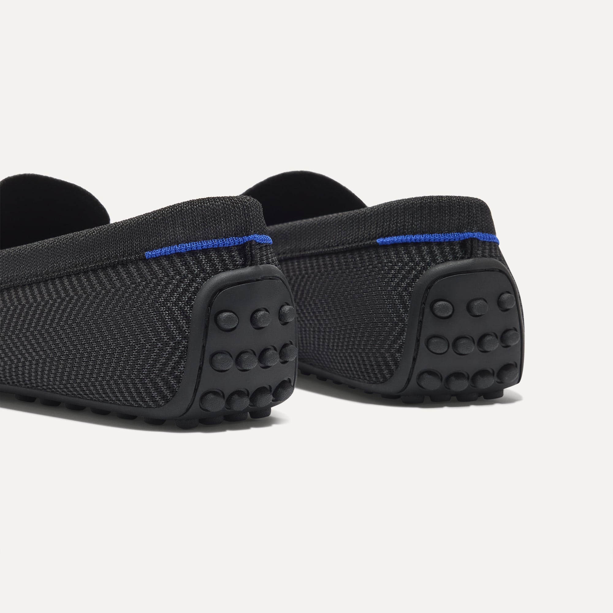 Close up of the heel of The Men's Daily Driver in Carbon Herringbone, with raised peg outsoles and Rothy's signature blue halo. 