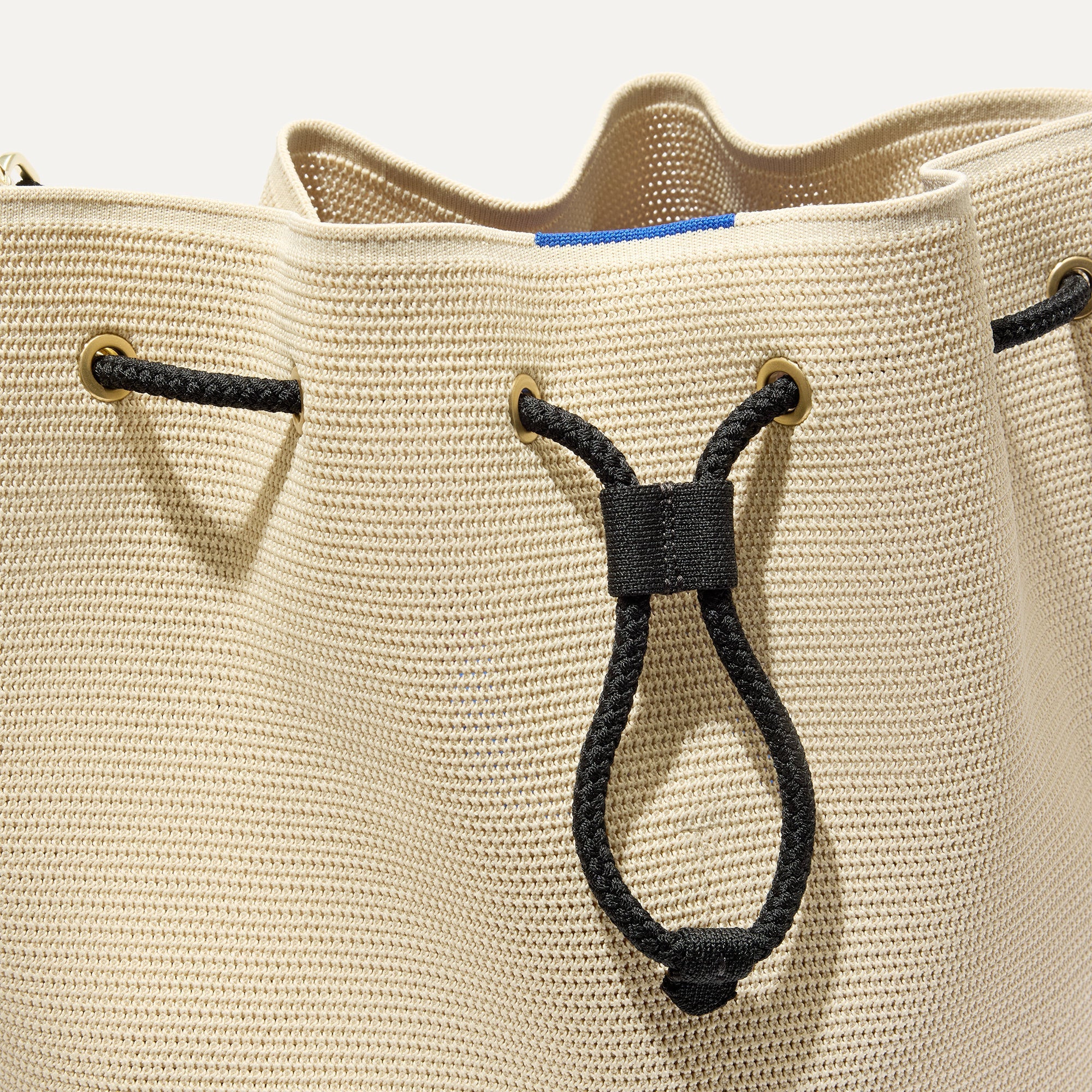 A close up of The Cinch Bucket Bag in Black and White Raffia-Knit showing the drawstring closure.