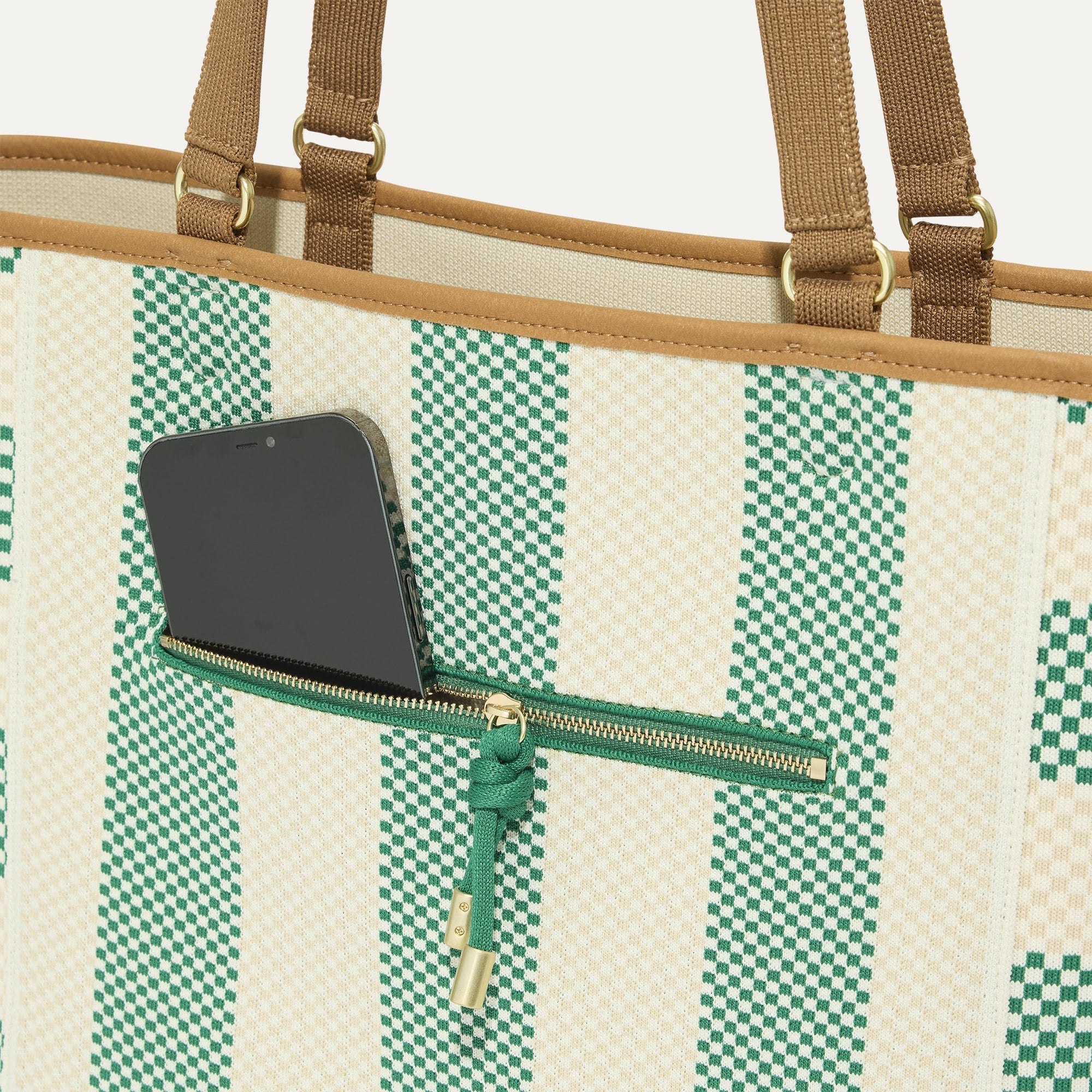 A closeup of The Two-Way Tote in Ivy, focusing on the exterior zip pocket.