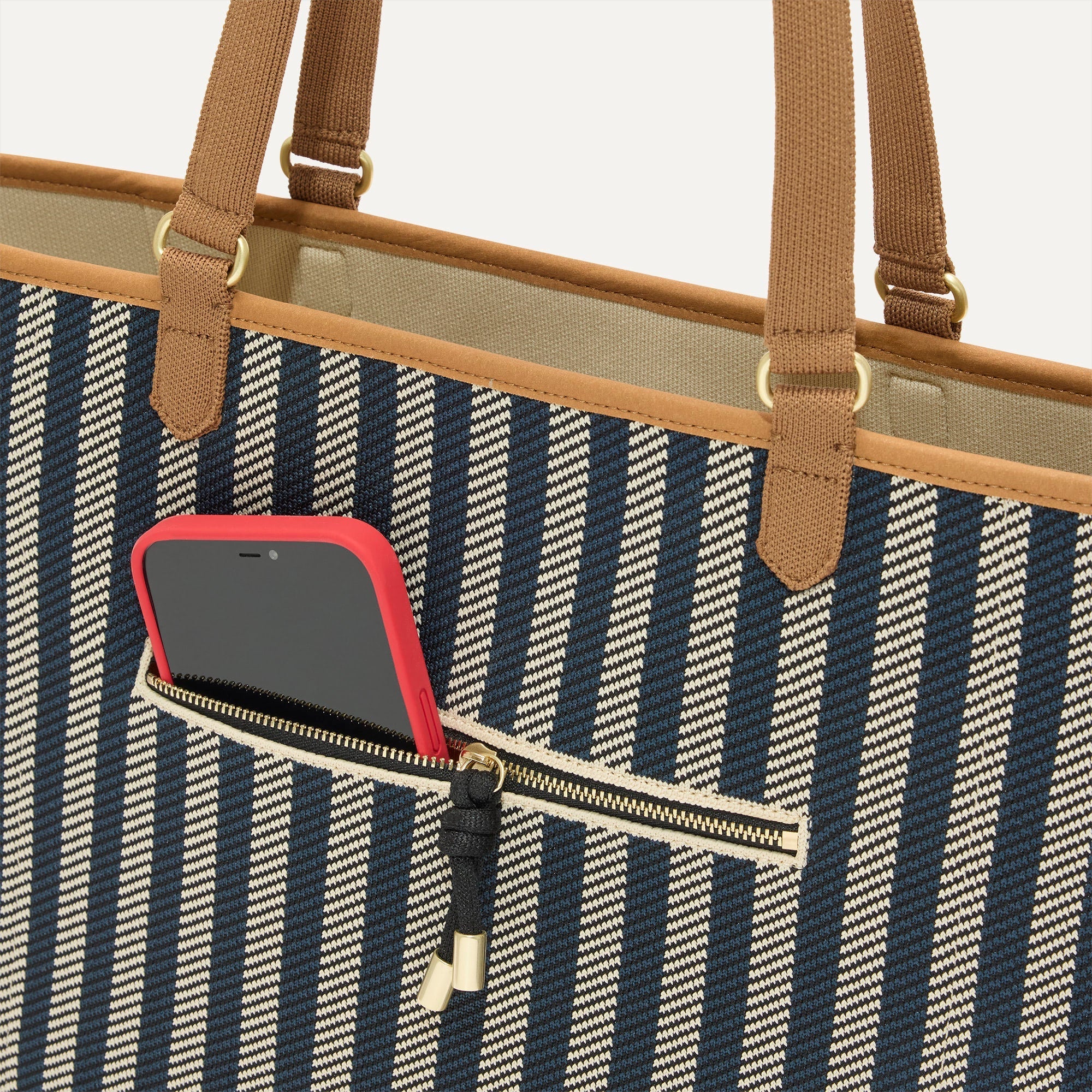 A closeup of The Two-Way Tote in Shadow, focusing on the exterior zip pocket.