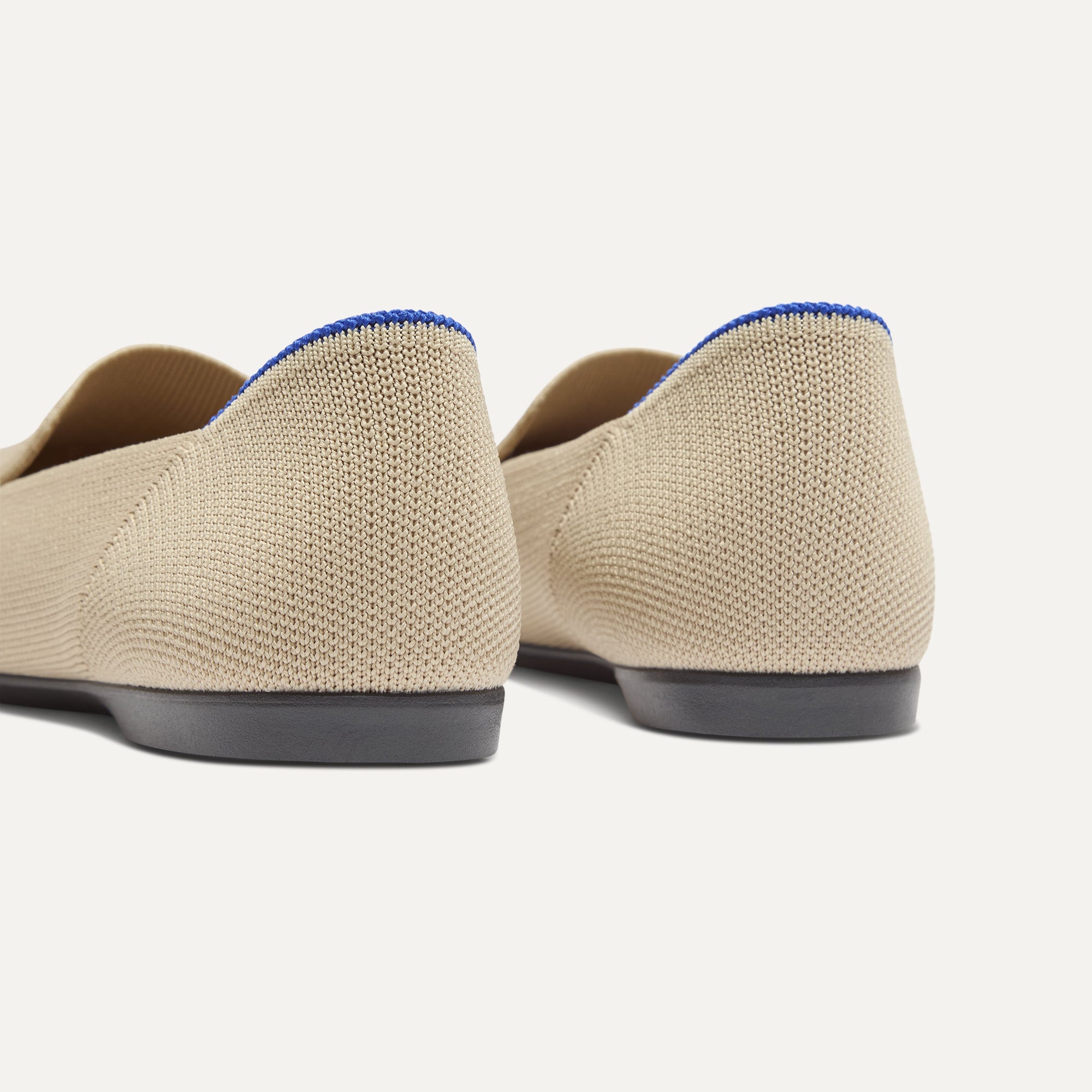 Close up of the heel of The Daily Loafer in Ecru, with raised peg outsoles and Rothy's signature blue halo. 