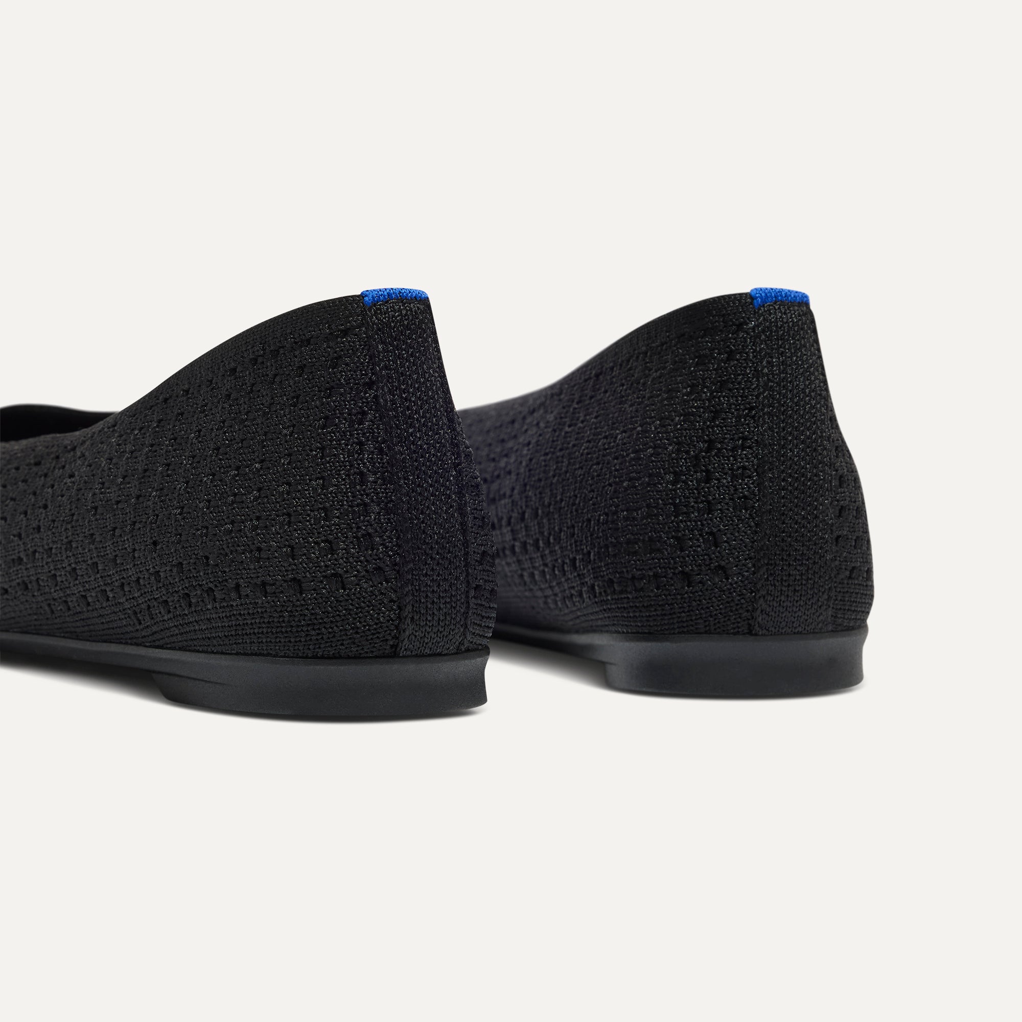 Close up of the heel of The Max Square Ballerina in Black Mesh with Rothy's signature blue halo.
