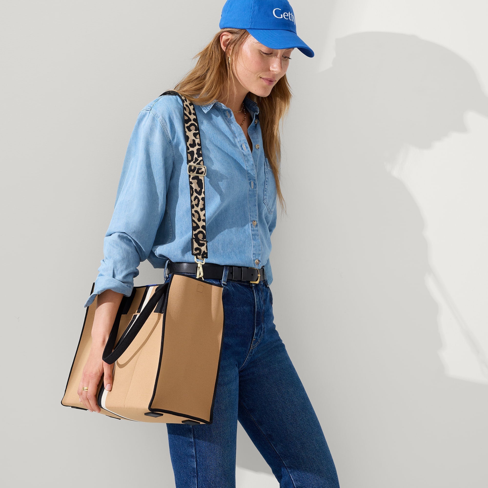 model | Overlay:: Shown with The Crossbody Strap (sold separately.) | Alt:: The Classic Tote in Grand Piano, worn as a crossbody by a model, shown from the side.